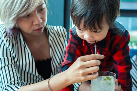 sigle mom help child drinking water from straw between working.の写真素材