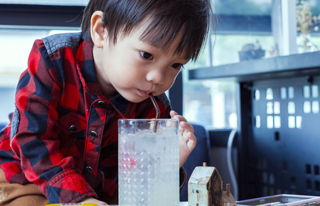 A child drinking water from straw.の写真素材