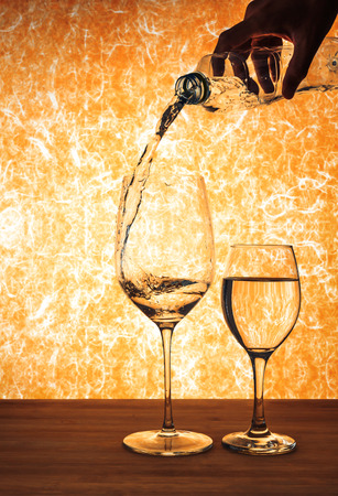 hand hole bottle and pouring water in to the wine glass.の写真素材