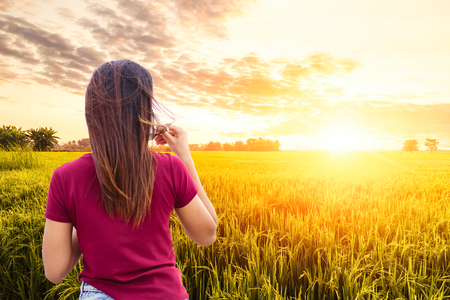 A women drink coffee in rice golden field.の写真素材