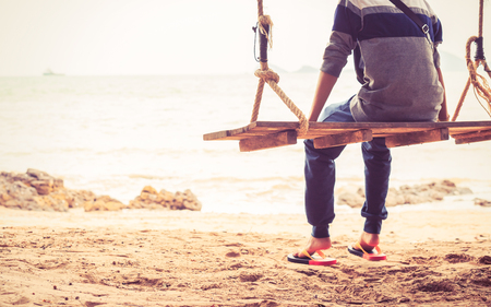 people sitting on the swing in the beach with sun light.の写真素材