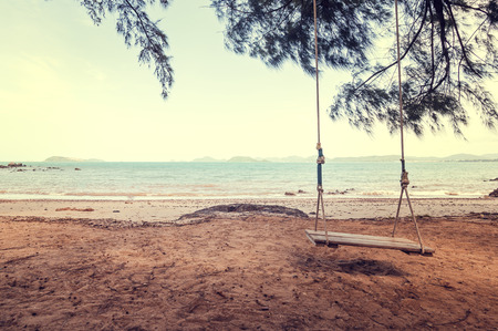 Swing on the beach under the tree with mountain back.の写真素材