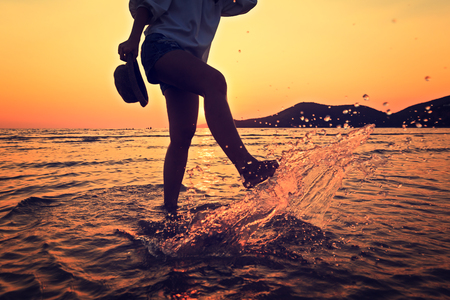 the women play water splash on the beach between sunset.の写真素材