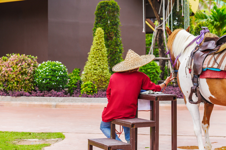 A man sitting near horse and him wear hat.の写真素材
