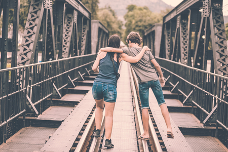 young couple hugging and walking on railの写真素材