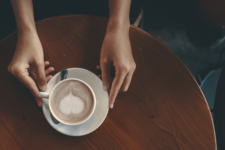 hands hold hot cup of coffee in the coffee shop.の写真素材