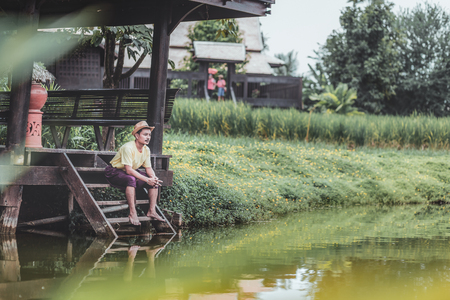 A man wear hat near the river for relax between travel.の写真素材