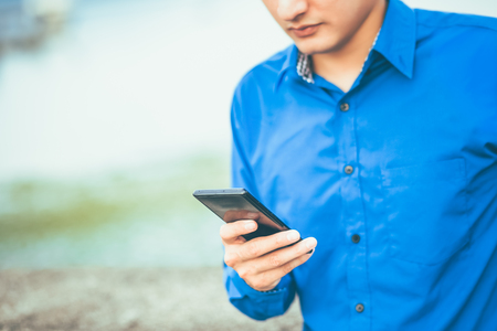 A businessman hold mobile phone for check message, e-mail and working.の写真素材