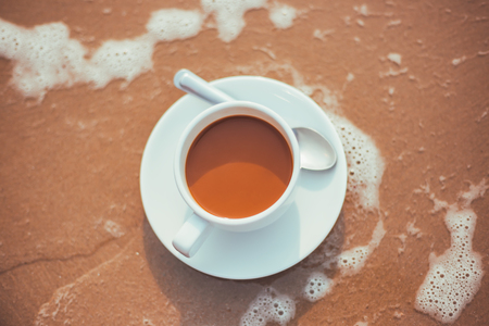 hot cup of coffee on  sand in the beach.の写真素材
