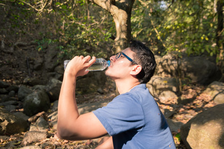 man drinking water from plastic bottle on in the forest. Pure nature relax  concept.