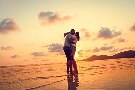 silhouettes in love romantic couple lovers hugging, smiling, touching, at sunset, sunrise on the background of the beach.の写真素材