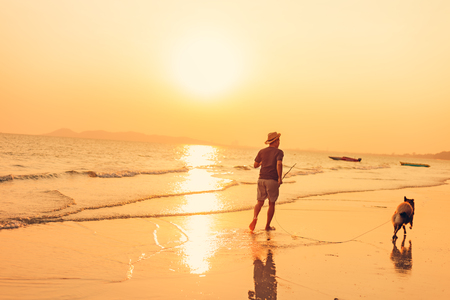 A man and a dog running on the beach and sunset, sunrise.の写真素材