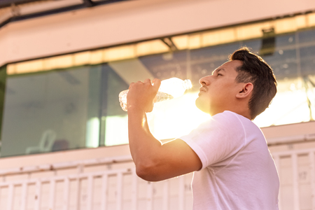 Caucasian man drinking water after exercises.の写真素材