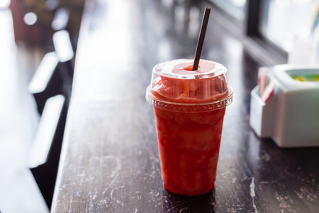 Strawberry Smoothie or Cocktail in a Glass with Straw on wood table.