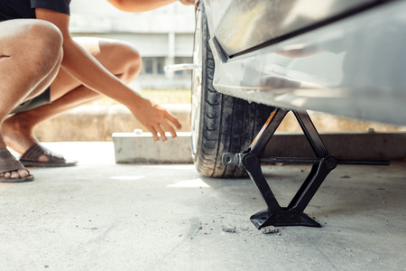 Car tire changed for maintenance in garage using hydraulic jack - car maintenance concept.の写真素材