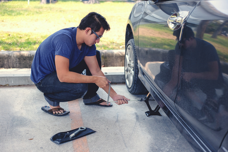 Hands using hydraulic jack - car maintenance concept. Car tire changed for maintenance in garageの写真素材