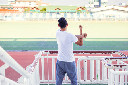 Full length portrait of a athletic man stretching in the morning and standing at sport stadium.の写真素材