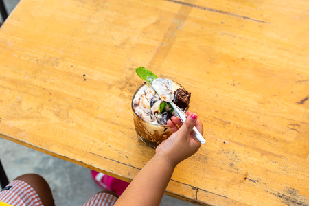 Adorable little girl use spoon pick ice cream chocolate on the table.の写真素材