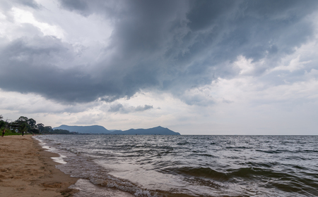 Rain cloud over the beach, mountain and sea water.の写真素材