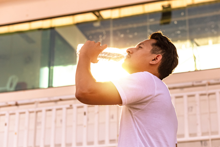 Caucasian man drinking water after exercises.の写真素材