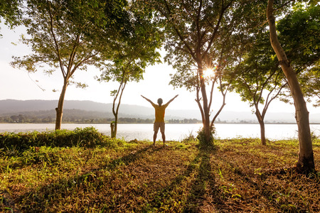 A man stand in the forest and near the water with mountain back.の写真素材
