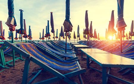 Beach loungers on deserted coast sea at sunrise.の写真素材