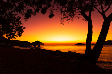 Silhouette beach, tree and mountain with sunset, sunrise. Seascape background.の写真素材