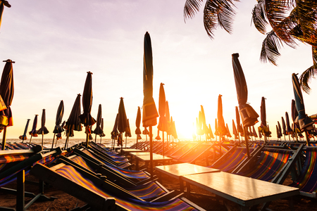Beach loungers on deserted coast sea at sunrise.の写真素材