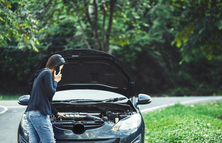 A women and broke down car on the road and she use mobile phone.の写真素材