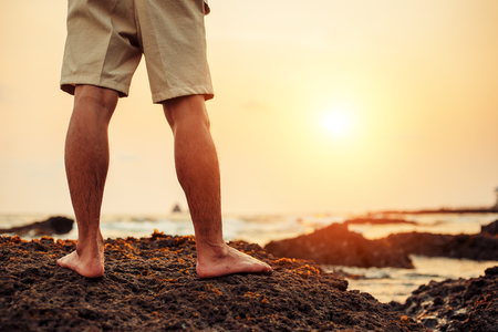 The man stand on the rock in the beach at sunset.の写真素材