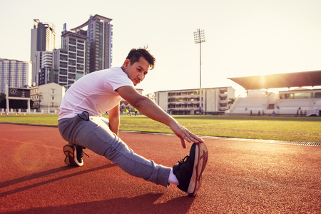 Full length portrait of a athletic man stretching at sport stadium.の写真素材