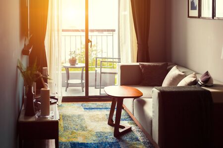 Sofa and table in the room. A chair out side the room on terrace.の写真素材