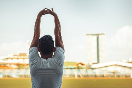 Full length portrait of a athletic man stretching in the morning and standing at sport stadium.の写真素材