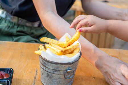 Children hands Picking French Fries on wood table.の写真素材