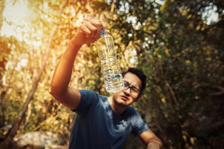 A man show few water in bottle in the forest and hot weather.の写真素材