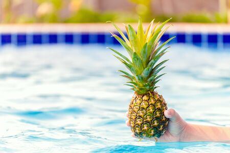 hand hold pineapple in the blue water.の写真素材