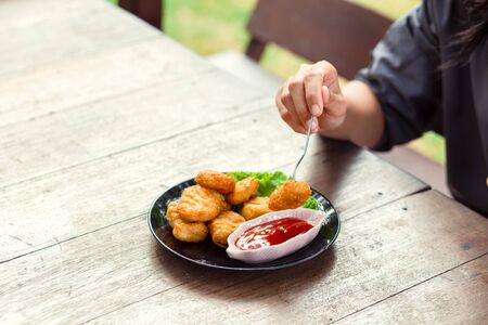 Chicken Nuggets impaled on a fork  and Dip sauce. A women eat Nuggets.の写真素材