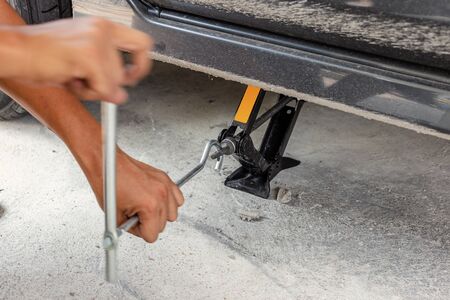 Hands using hydraulic jack - car maintenance concept. Car tire changed for maintenance in garageの写真素材