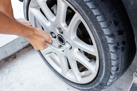 Man changing tire with wheel wrench