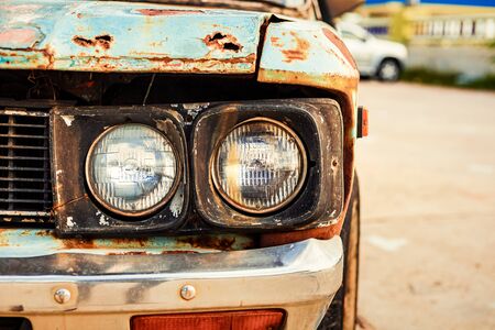 headlights of old car with cracked and peeling paint at park.の写真素材