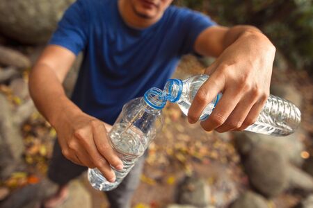 Hands hold water bottle and pour water.の写真素材