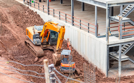 The orange backhoe and Mini excavator is on the ground at site construction.
