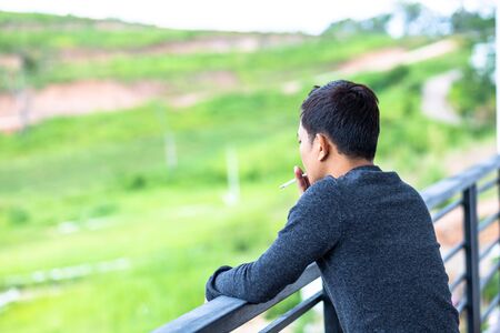 A man smoking  on  balcony at the hotel.の写真素材