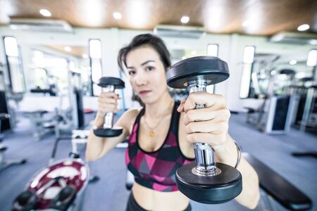 athletic woman training hard with dumbells at fitness. Fitness and healthy lifestyle conceptの写真素材