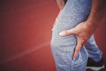 Athlete suffering form running knee or kneecap injury during outdoor workout.の写真素材