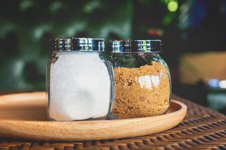 Sugar in pot on wood plate near cup of coffee.の写真素材