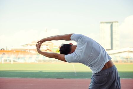 Full length portrait of a athletic man stretching at sport stadium.の写真素材