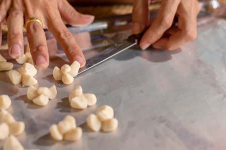 Woman cuts dough for baking knife, dough lying on board.の写真素材