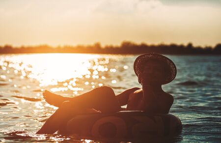 A man ware hat and he is on swim tube in the water.の写真素材