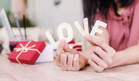 hand holding the word love near the gift box on the table.の写真素材